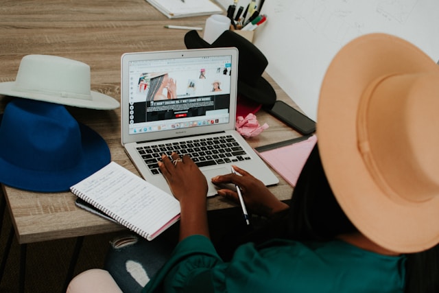 A lady putting on a hat using a computer