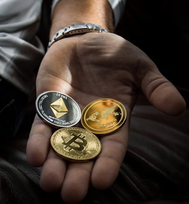A hand showing three crypto coins