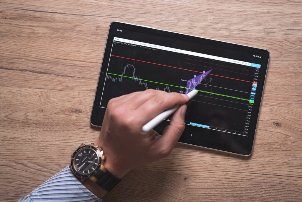 Person Holding Pen and Digital Tablet on Brown Wooden Surface